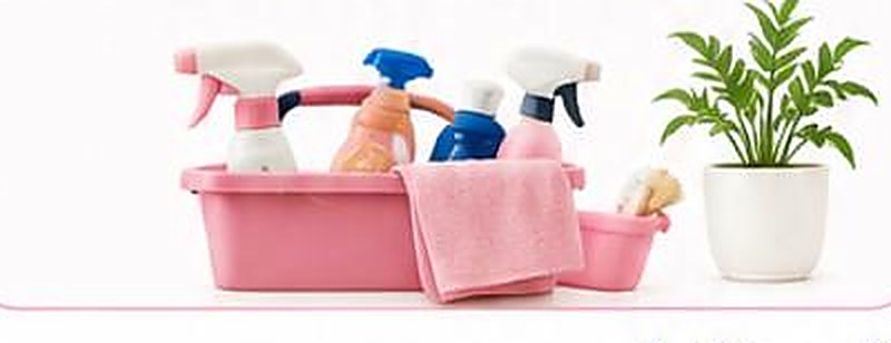 Cleaning sprays and cloths arranged in a pink caddy beside a potted plant.